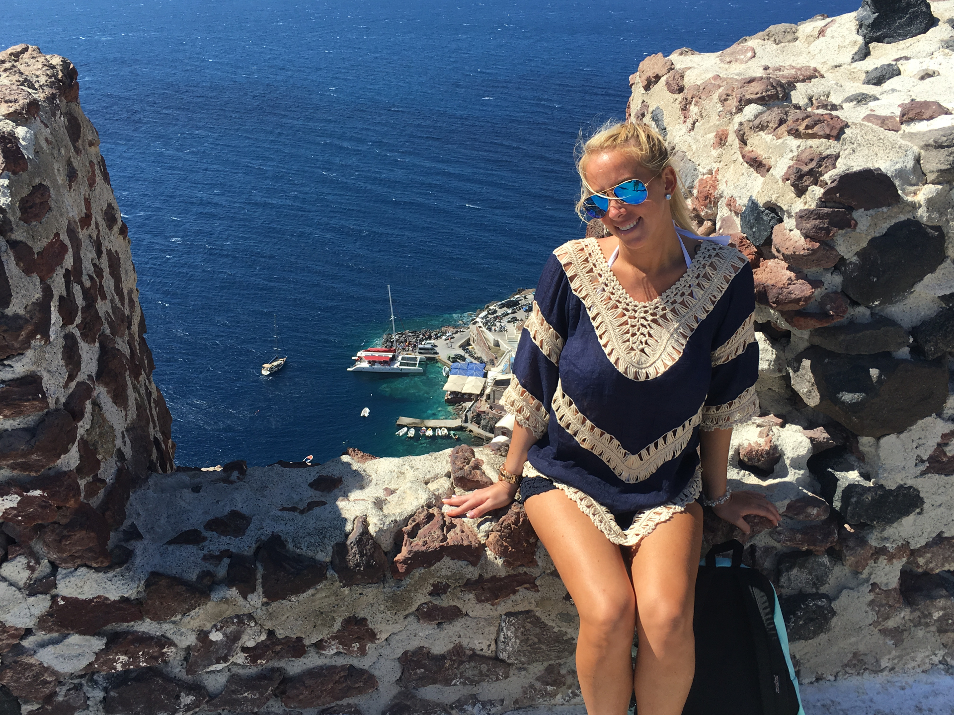 Alyssa perched on a cliffside wall over deep blue water