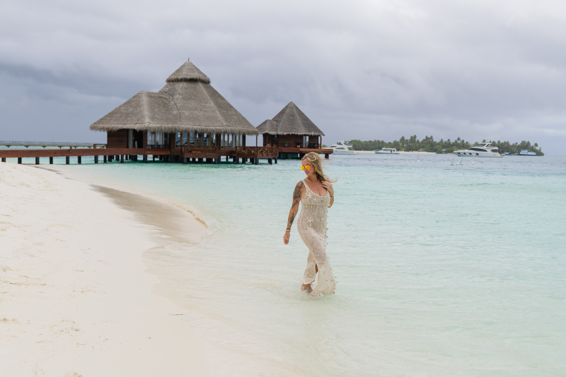 Alyssa walking a Maldives beach past overwater villas